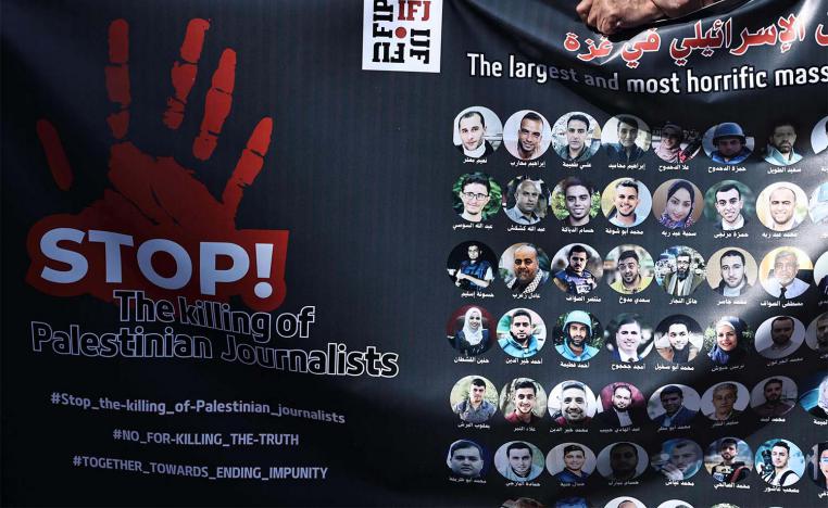 Protesters carry a banner bearing pictures of slain Palestinian journalists during a rally to condemn their killing