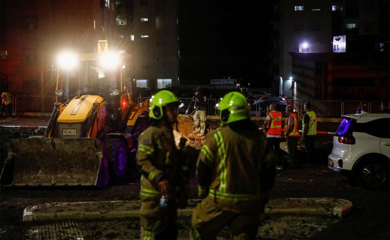 Israeli rescue force members inspect the site where a projectile fell amid cross-border hostilities between Hezbollah and Israel in Haifa