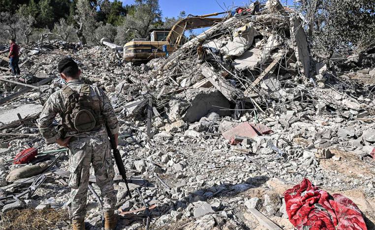 A Lebabese army soldier stands by the rubble of a destroyed building at the site of a previous Israeli air strike on the village of Aito in northern Lebanon