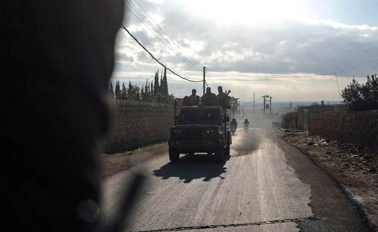 Fighters from Hayat Tahrir al-Sham (HTS) ride in military vehicles in the eastern outskirts of the town of Atarib,