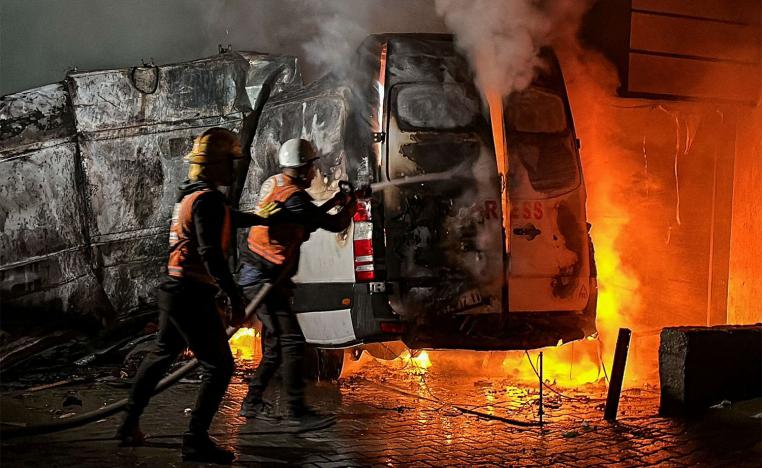 Civil Defense members put out a fire in a broadcast van following an Israeli strike that killed the five journalists