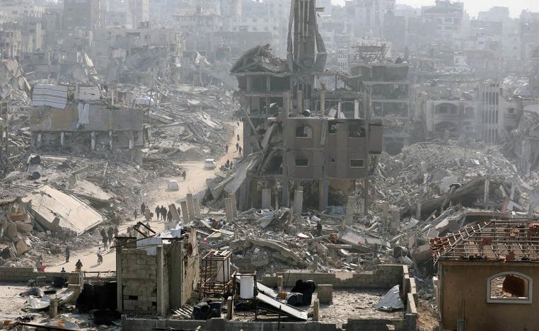 People walk past the rubble of destroyed buildings in Jabalia