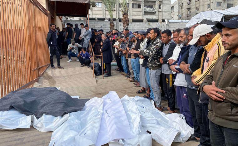 Palestinians pray by the bodies of casualties of Israeli strikes, outside the Nasser hospital in Khan Yunis