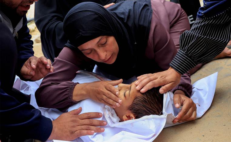 Mourners react as they look at the body of a Palestinian boy killed in an Israeli strike