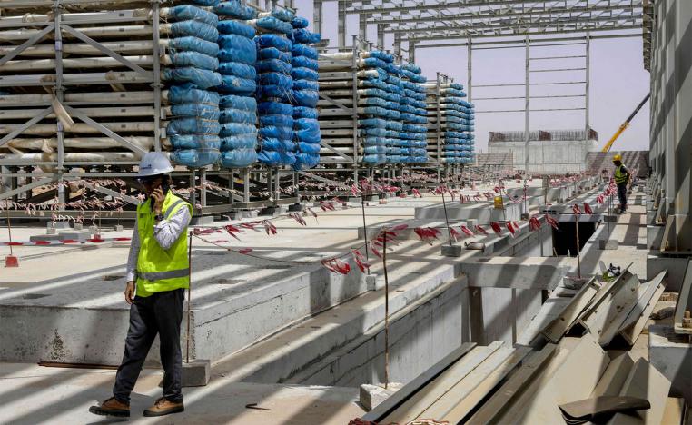 Workers stand near next to heavy equipment during the construction of a desalination plant in Dakhla