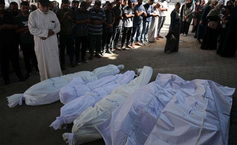 Mourners pray next to shrouded bodies during the funeral of Palestinians killed in an overnight strike on a tent in Gaza City