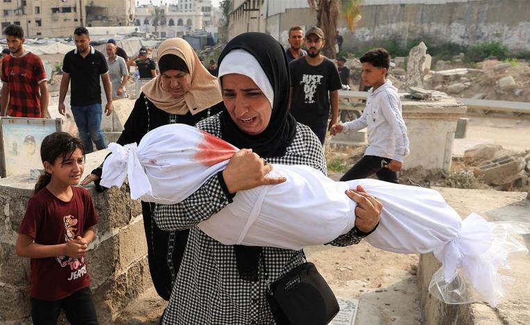 Palestinian woman Soha Tafesh carries the body of her granddaughter Sarah Abu Daf, who was killed in an early morning Israeli strike on a house