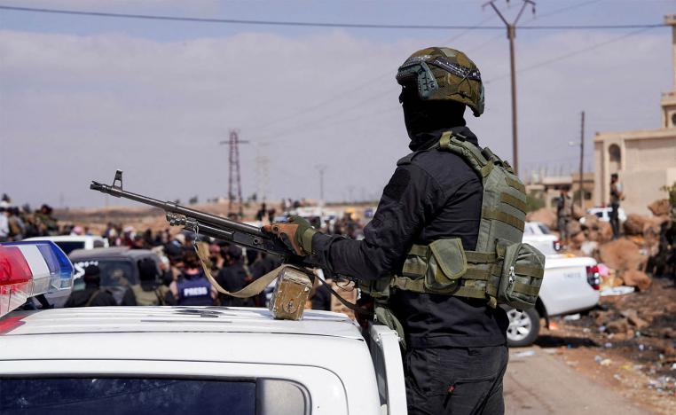 A member of Internal Security Forces holds a gun at an Internal Security Forces checkpoint in Syria