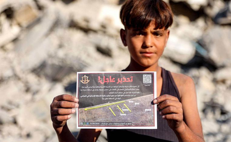A boy holds one of the leaflets dropped by the Israeli military on Gaza City, urging evacuation south to al-Mawasi