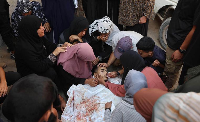 Palestinians mourn by the body of a relative killed in Israeli strikes on Gaza City at dawn
