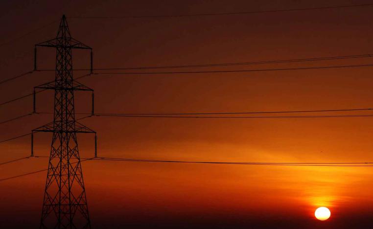 The sun is seen behind high-voltage power lines and electricity pylons at a highway northeast of Cairo.