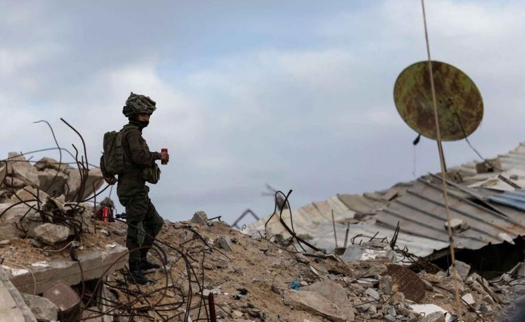 An Israeli soldier holds a drink as he stands on rubble in Rafah in the southern Gaza Strip, December 8, 2025. 
