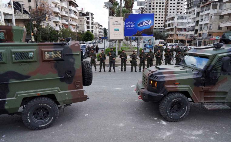 Members of the Syrian Security forces stand guard near military vehicles on the day people from the Alawite sect protest as they demand federalism, in Latakia, Syria, December 28, 2025. 