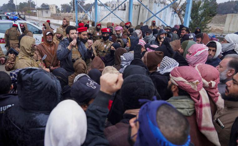 A member of Syrian military police speaks to relatives of detainees gather near al-Aqtan prison in Raqqa