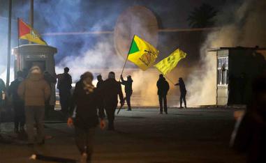 A protester holds a Kataib Hezbollah flag as supporters of Iraqi Shiite armed group's attempt to move toward the US embassy in Baghdad