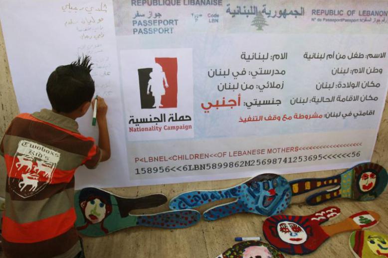 A child writes his name on a banner during a demonstration for the right to Lebanese nationality in Beirut