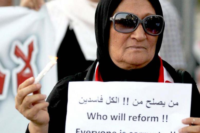 An Iraqi woman holds a sign and a candle during a demonstration in Baghdad’s Tahrir Square, on July 31