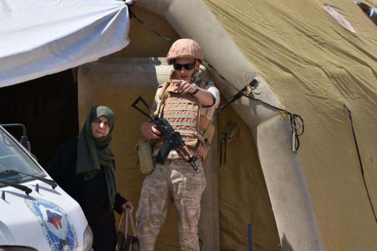  A Russian soldier guides a Syrian woman at the Abu Duhur crossing on the eastern edge of Idlib province, on August 20. 
