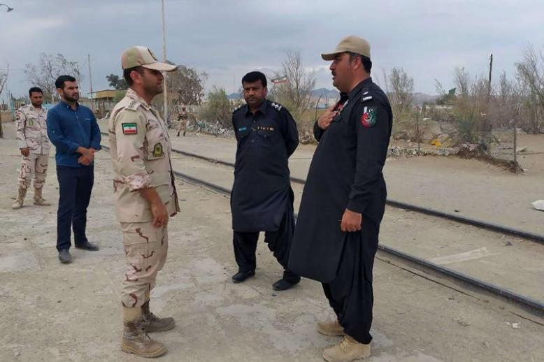 A Pakistani border security official (R) and an Iranian border official meet at Zero Point in the Pakistan-Iran border town of Taftan, on October 16