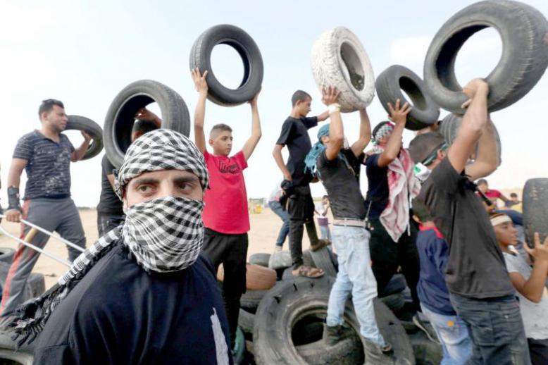 Palestinian demonstrators hold tyres during a protest at the border fence in southern Gaza, on October 19