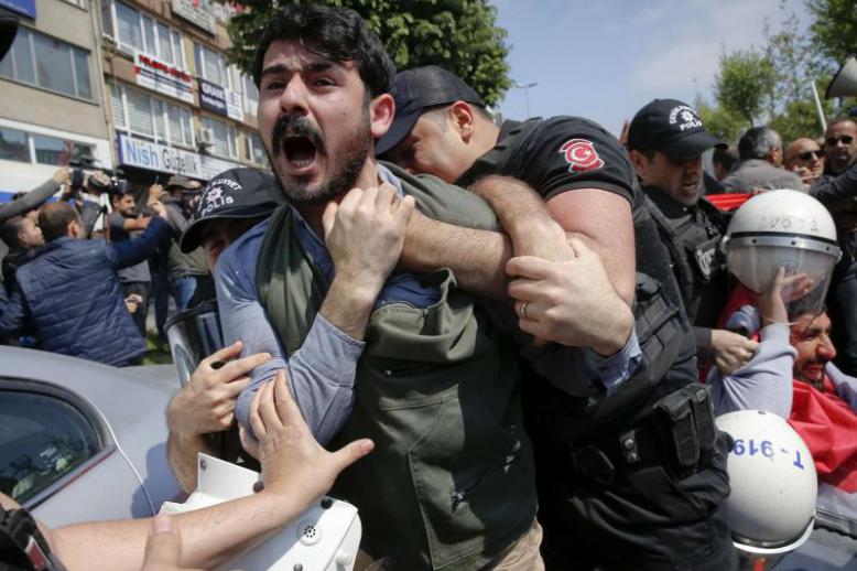 A demonstrator screams as police officers grab him during a protest in Istanbul