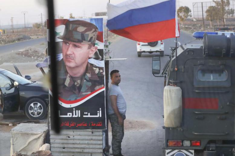 A shift in direction. A Syrian soldier stands at a checkpoint as a Russian military police vehicle passes by near the village of Almajdiyeh, last August.