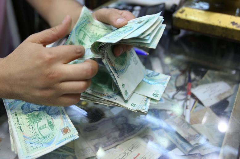 A shopkeeper counts money in his shop at a bazaar in Tunis