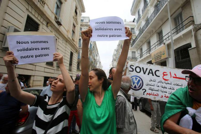 Workers carry signs in solidarity with Mourad Eulmi, the head of the Algerian family-owned firm SOVAC, a partner of Volkswagen AG, questioned in court about corruption accusations in Algiers