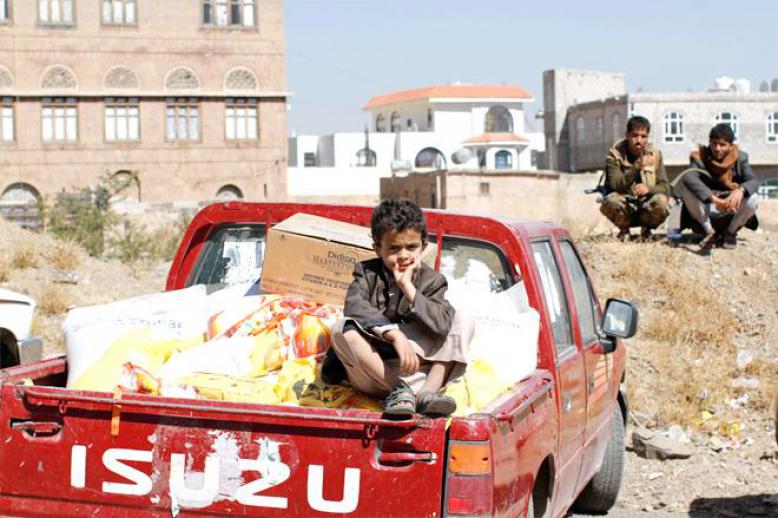 A son of a Houthi supporter sits on the back of a truck with food aid in Sana’a