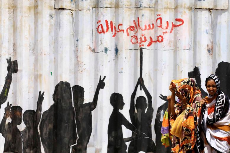 سودانيات بالقرب من جدارية عن شعارات الثورة