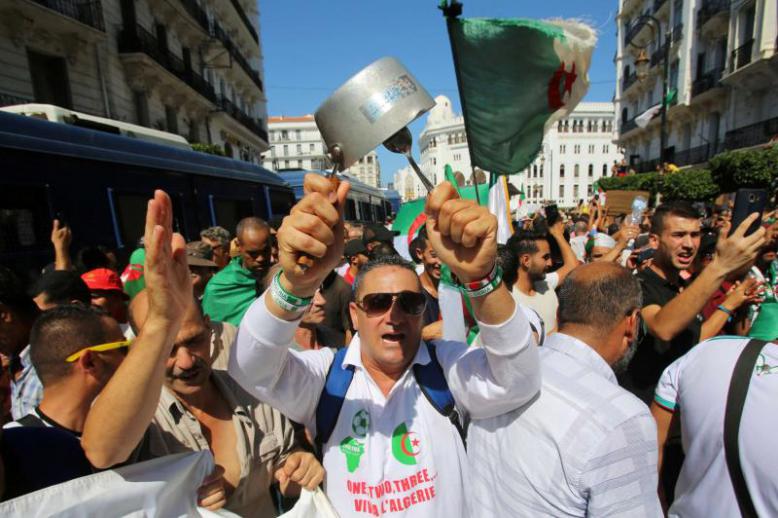 A demonstrator bangs a pot during a protest demanding social and economic reforms as well as the departure of the country’s ruling elite in Algiers