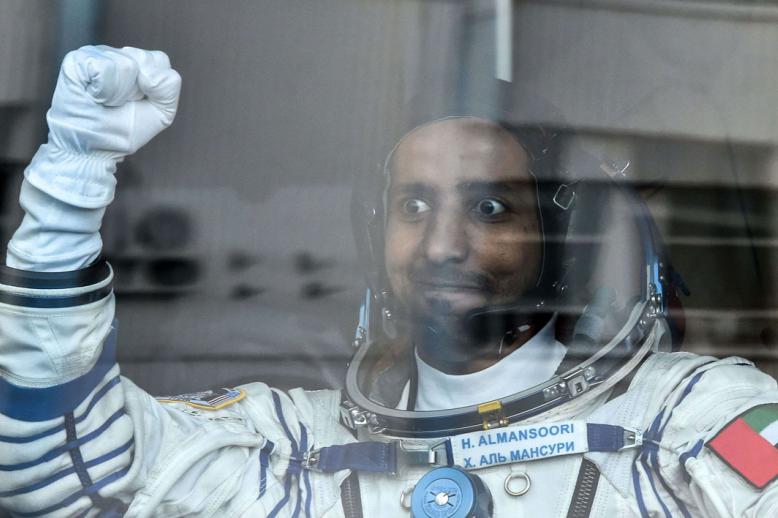 United Arab Emirates' astronaut Hazza Al Mansouri raises his fist from a bus before boarding a Soyuz rocket to the International Space Station