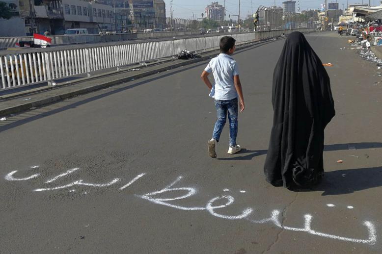 أم عراقية وابنها يمران في منطقة الاعتصامات في بغداد