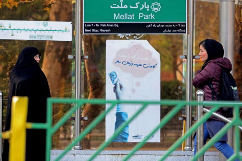 Iranian women walk past a bus station in Tehran