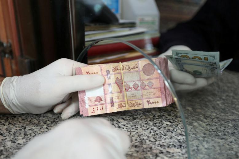 A customer wearing gloves holds Lebanese pounds at a currency exchange store
