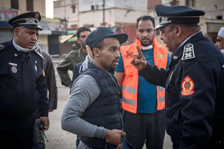 Moroccan policeman, patrolling as part of a larger combined security force, instructs a man to return home