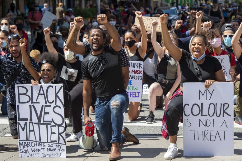 Anti-racism demonstrators take a knee near Toronto Police Headquarters during a march on Saturday, June 6, 2020, protesting the death of George Floyd