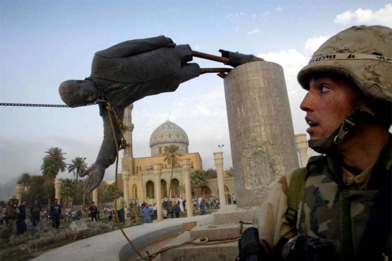 A US Marine Corp watches as a statue of Iraq's President Saddam Hussein falls in central Baghdad's Firdaus Square in April 2003