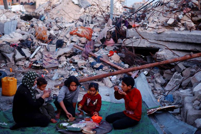 عائلة فلسطينية تتناول طعام الافطار أمام منزلها المدمر في غزة
