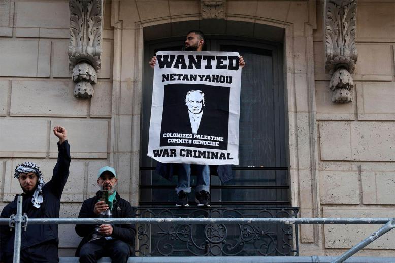 A protestor holds a poster bearing a wanted announcement for Israeli OM  during a protest in Paris