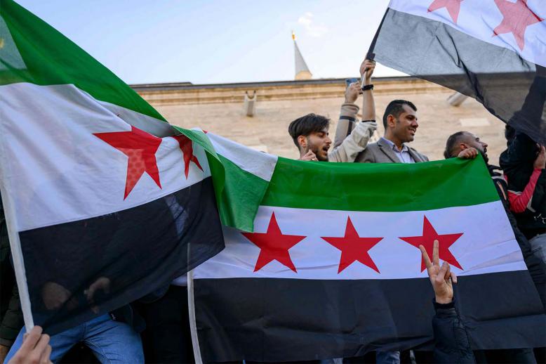 Syrian residents in Turkey hold Syrian flags as they celebrate the end of the Baath rule in Syria 