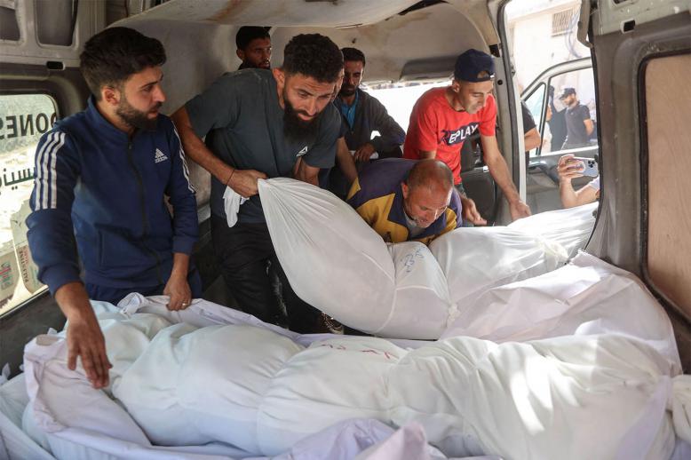 People unload the shrouded bodies of people killed in an Israeli strike, at Al-Shifa hospital in Gaza City 