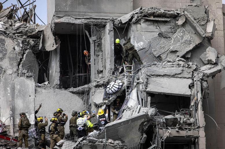 Israeli emergency services and security officers evacuate a body from the rubble of a building hit by an Iranian missile in Beersheba in southern Israel 