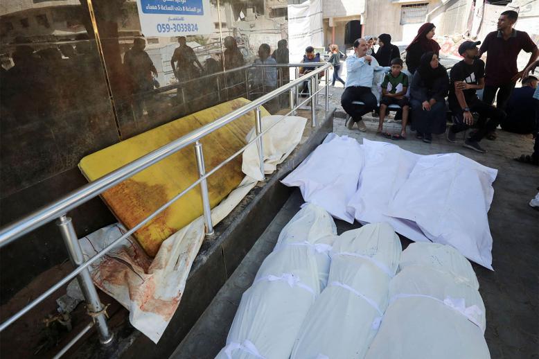 Mourners sit next to dead bodies during the funeral of Palestinians killed in an Israeli strike 