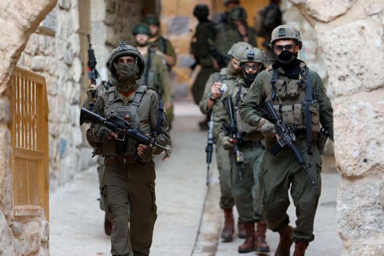 Israeli soldiers walk during a weekly settlers tour in Hebron