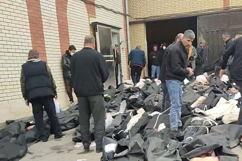 Bodies lie in body bags on the ground as people stand amid the scene outside Kahrizak Forensic Medical Centre in Tehran
