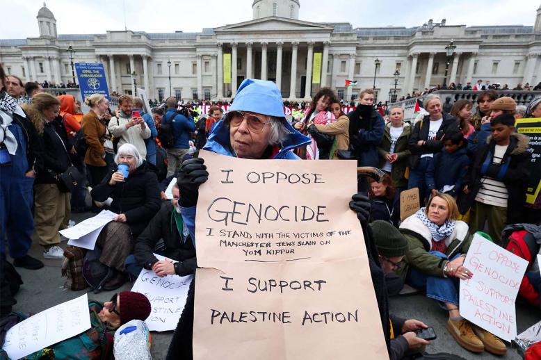 A protester holds a placard during a mass demonstration organised by Defend our Juries, against the British government's ban on Palestine Action at Trafalgar Square in London October 4, 2025