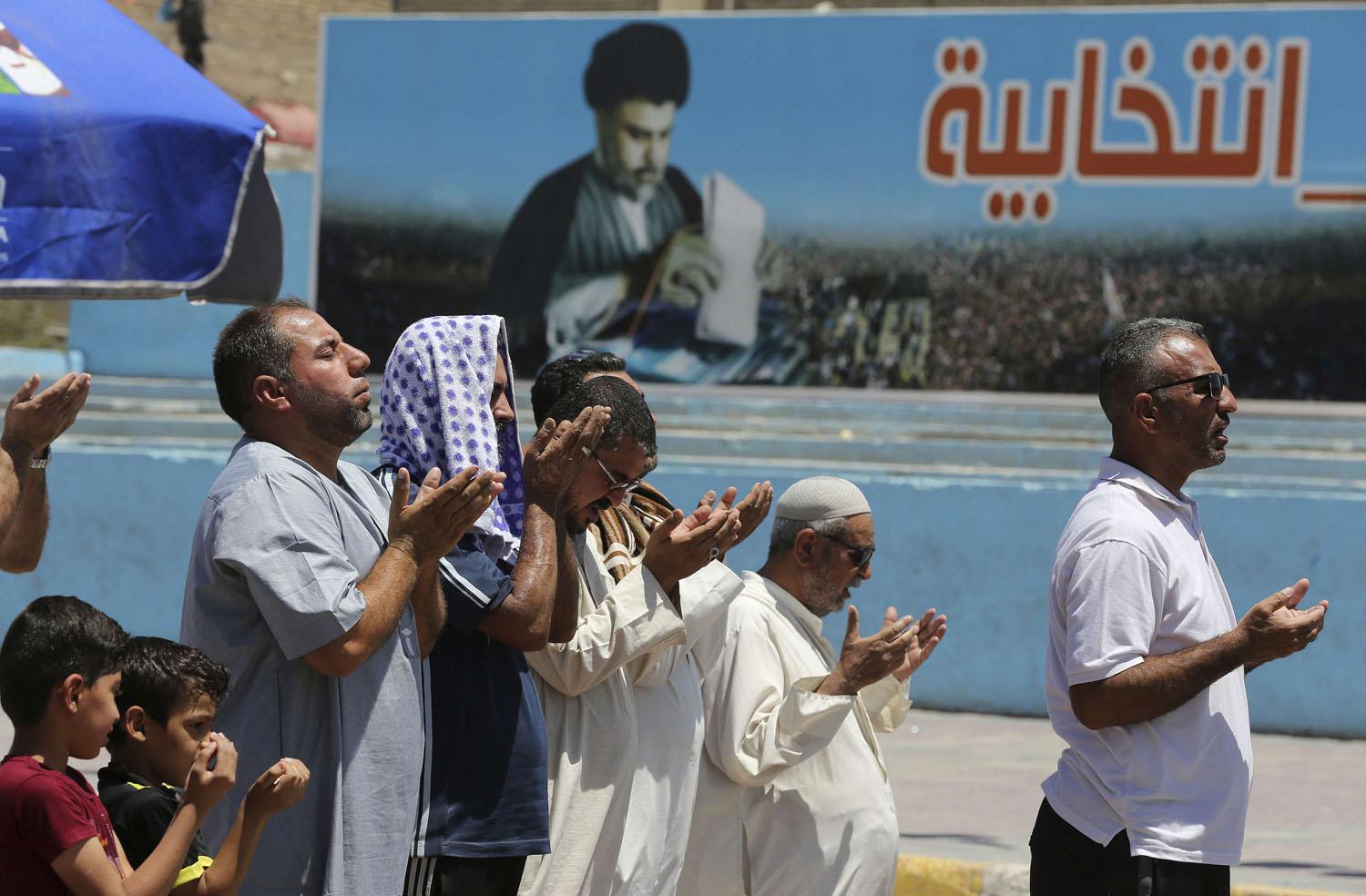عراقيون يصلون أمام مصلق انتخابي للتيار الصدري