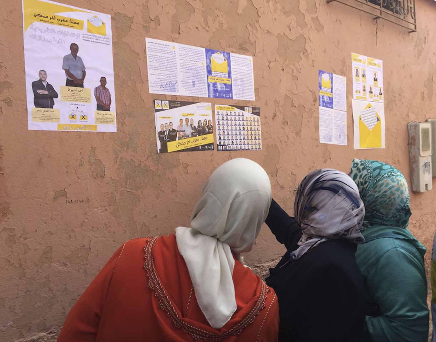 مغربيات يقرأن ملصقات انتخابية