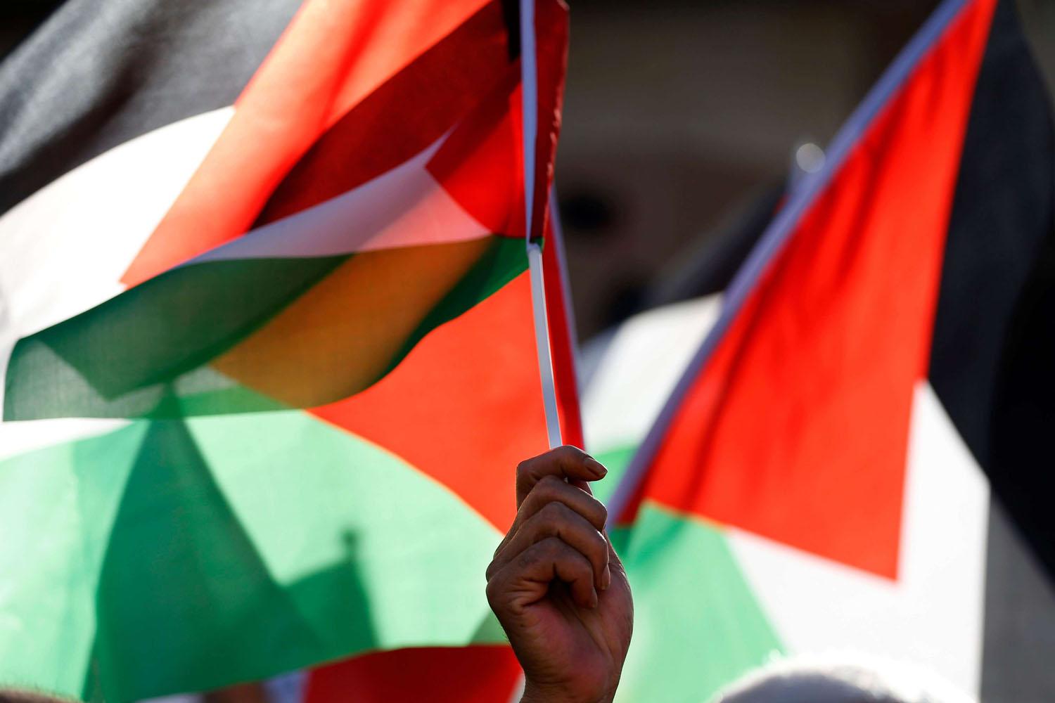 فلسطيني يرفع أعلام بلاده في رام الله